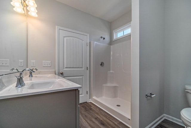 full bathroom featuring wood finished floors, baseboards, double vanity, a shower, and toilet