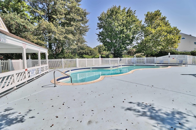 pool with a patio area and fence