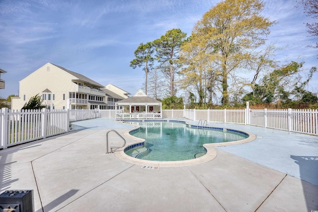 community pool featuring a patio area, an outbuilding, and fence