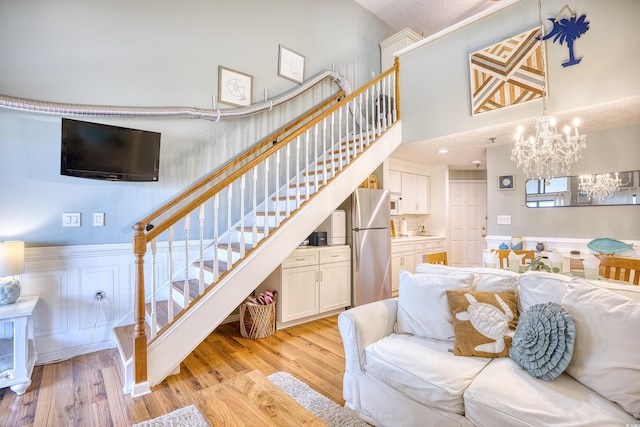 stairs featuring a chandelier, a high ceiling, and wood finished floors