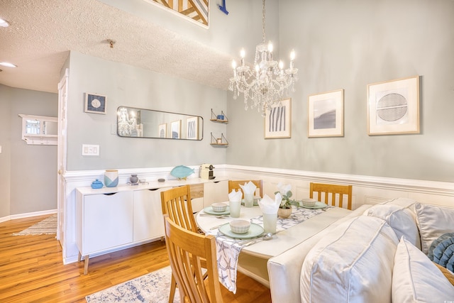 dining room featuring a chandelier, a textured ceiling, and wood finished floors