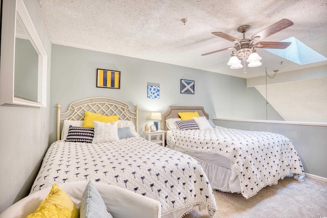 carpeted bedroom with vaulted ceiling with skylight, a ceiling fan, baseboards, and a textured ceiling