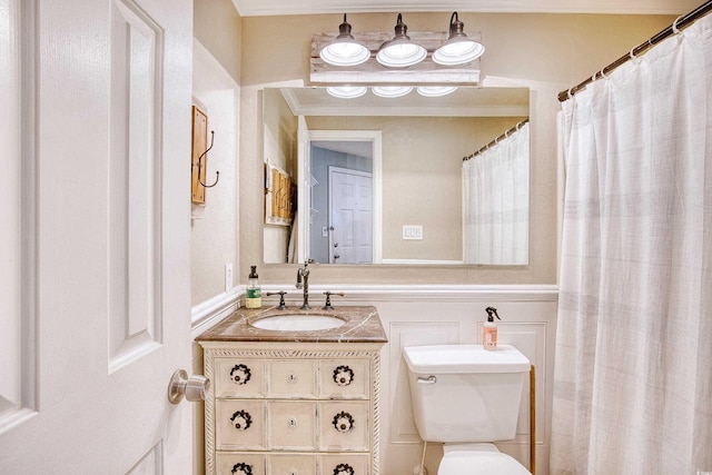 full bath with vanity, a decorative wall, and toilet