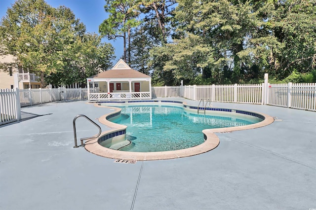 community pool featuring an exterior structure, an outbuilding, fence, and a patio area