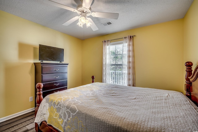 bedroom with visible vents, a textured ceiling, and a ceiling fan