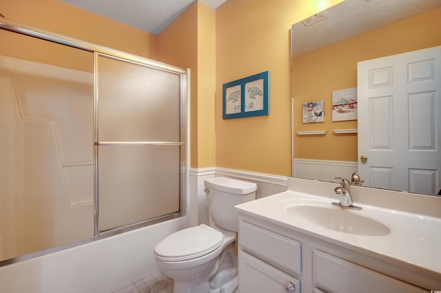 full bath featuring a textured ceiling, toilet, vanity, and wainscoting