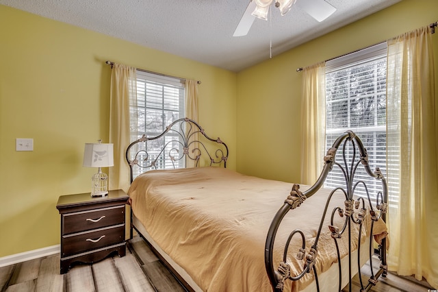 bedroom featuring ceiling fan, wood finished floors, baseboards, and a textured ceiling