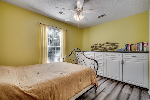 bedroom with visible vents, a textured ceiling, and wood finished floors