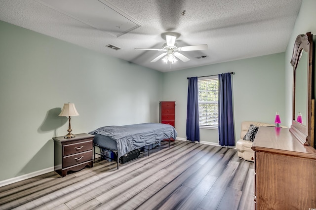 bedroom featuring visible vents, a textured ceiling, attic access, and wood finished floors