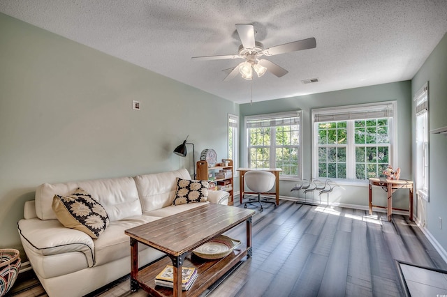 living area featuring visible vents, baseboards, wood finished floors, a textured ceiling, and a ceiling fan