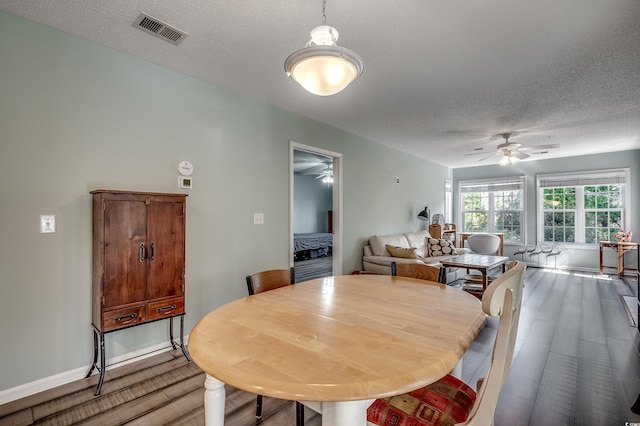 dining space with baseboards, visible vents, light wood finished floors, ceiling fan, and a textured ceiling