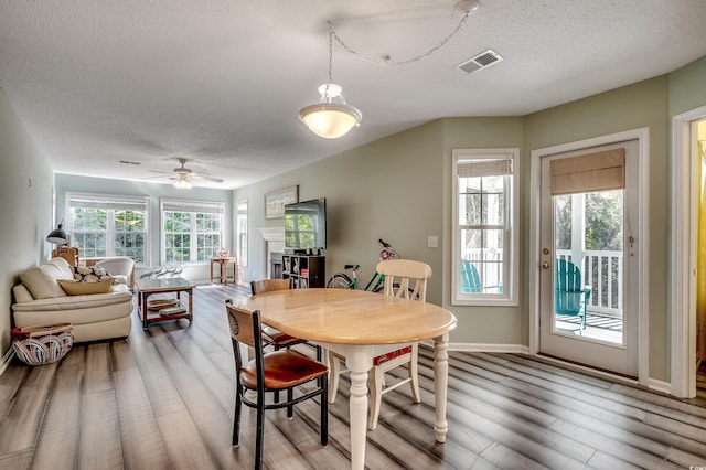 dining area with a textured ceiling, visible vents, light wood-type flooring, and ceiling fan