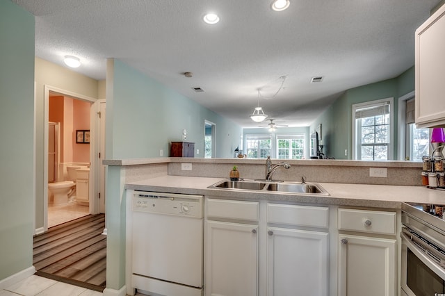 kitchen with light countertops, visible vents, white dishwasher, and a sink