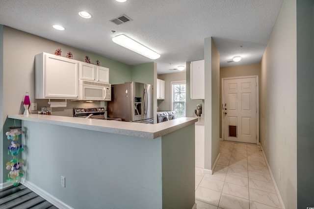 kitchen with visible vents, a peninsula, stainless steel appliances, washing machine and dryer, and marble finish floor