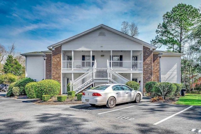 view of property with stairway and uncovered parking