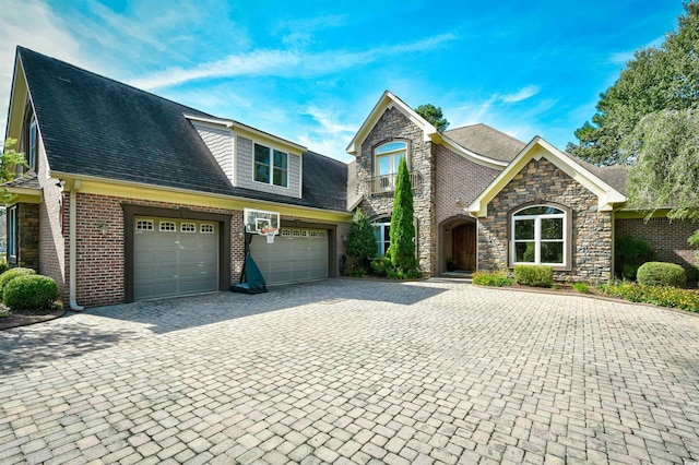 view of front of property with a garage, decorative driveway, stone siding, and a shingled roof