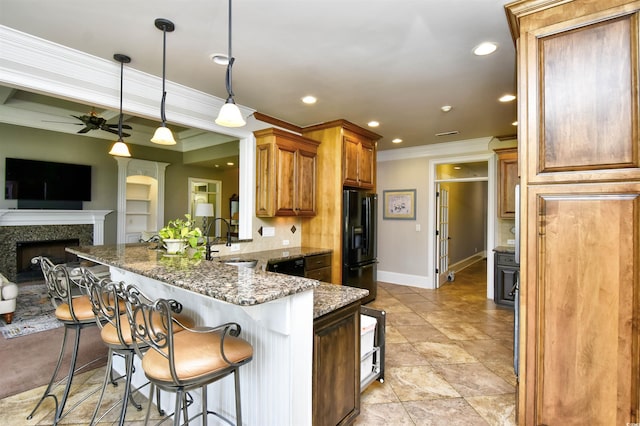 kitchen featuring a kitchen breakfast bar, a peninsula, black refrigerator with ice dispenser, a ceiling fan, and a sink