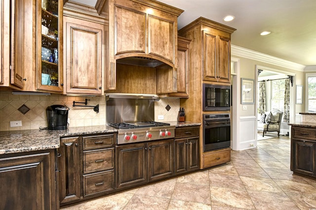 kitchen with dark stone counters, glass insert cabinets, black appliances, and ornamental molding