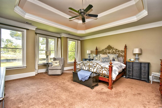 carpeted bedroom with a tray ceiling and ornamental molding