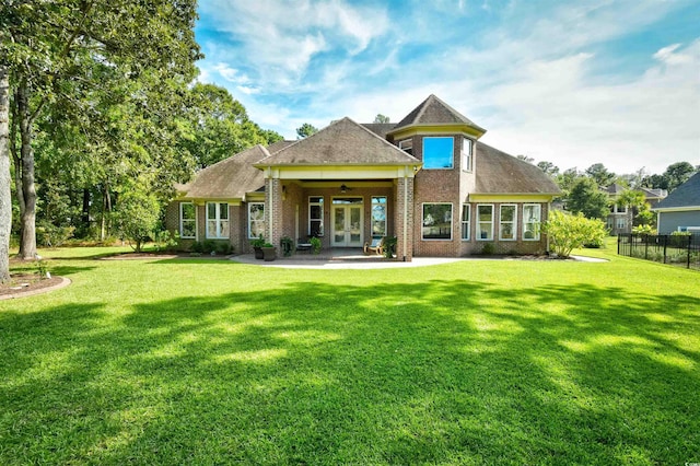 rear view of property with a ceiling fan, french doors, fence, and a lawn