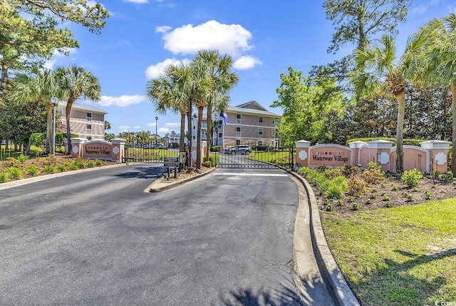 view of street featuring a gated entry, curbs, and a gate