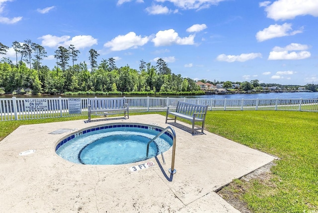 view of swimming pool with a yard, fence, a water view, and a hot tub