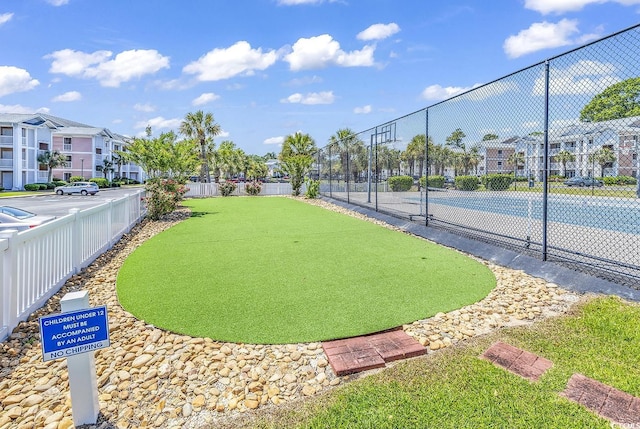 surrounding community with a residential view, a tennis court, and fence