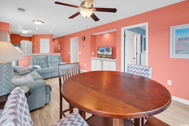 dining area with light wood-style floors, a ceiling fan, visible vents, and baseboards