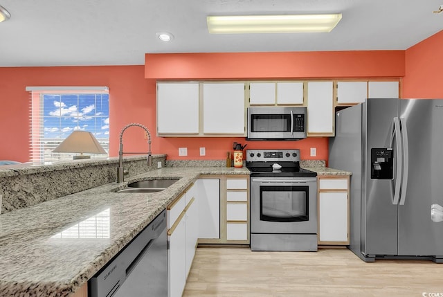 kitchen with a sink, appliances with stainless steel finishes, light wood-style flooring, and white cabinetry