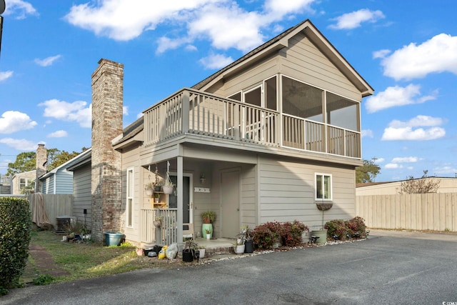 exterior space with a balcony, cooling unit, fence, and a chimney