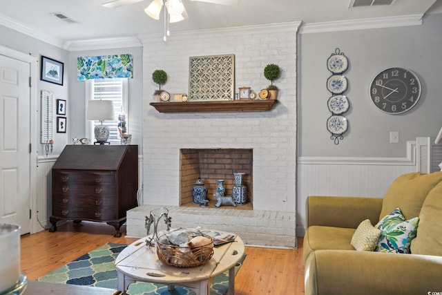 living area featuring visible vents, ornamental molding, a ceiling fan, and wood finished floors