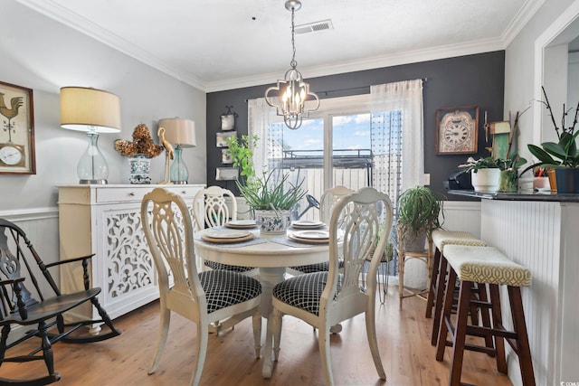 dining area with visible vents, ornamental molding, an inviting chandelier, and wood finished floors