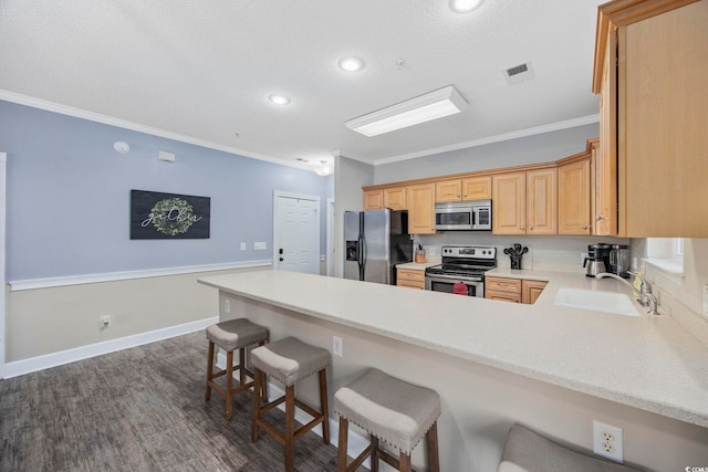 kitchen featuring visible vents, a peninsula, a sink, appliances with stainless steel finishes, and crown molding