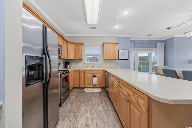 kitchen featuring visible vents, a peninsula, a sink, light countertops, and appliances with stainless steel finishes