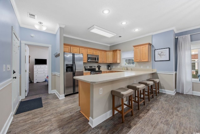 kitchen featuring visible vents, a peninsula, stainless steel appliances, light countertops, and a kitchen breakfast bar