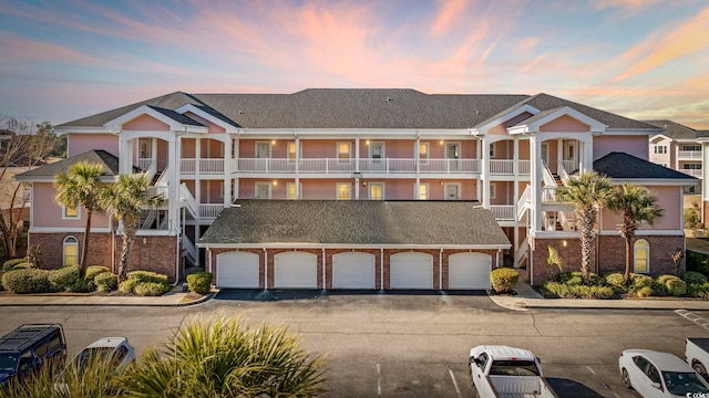 townhome / multi-family property with brick siding, stairway, and driveway