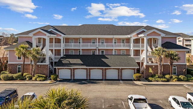 multi unit property featuring brick siding, stairway, driveway, and an attached garage