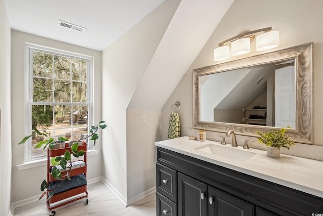 bathroom with vanity, lofted ceiling, baseboards, and visible vents