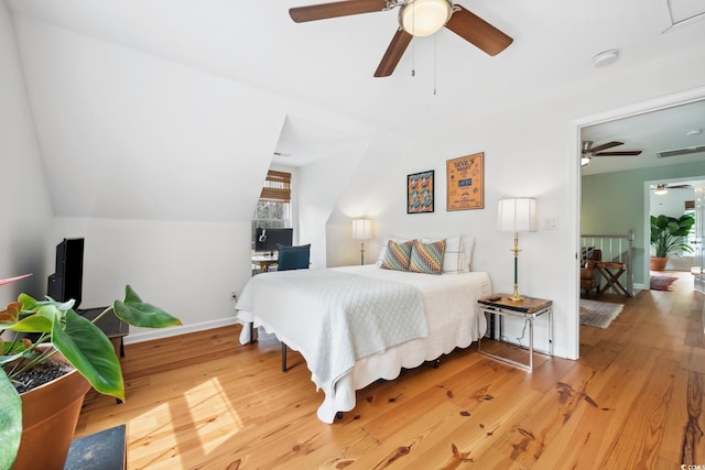 bedroom with lofted ceiling, baseboards, visible vents, and wood-type flooring