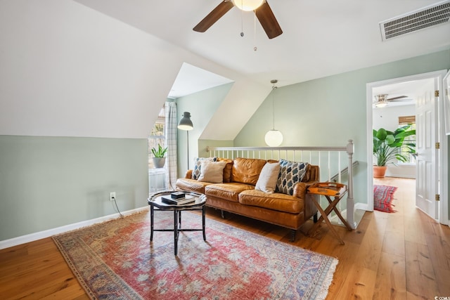 living room with visible vents, lofted ceiling, wood-type flooring, baseboards, and ceiling fan