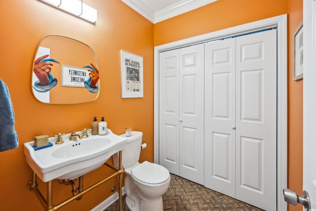 bathroom featuring a sink, a closet, toilet, and crown molding