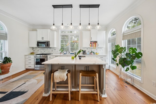 kitchen featuring a breakfast bar, ornamental molding, backsplash, and stainless steel appliances