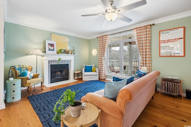 living area with wood finished floors, crown molding, and a tile fireplace