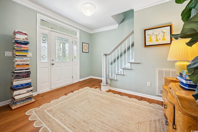 foyer entrance with visible vents, baseboards, stairs, ornamental molding, and wood finished floors