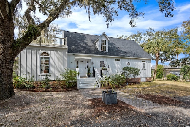 view of front of house with board and batten siding, a shingled roof, and a balcony