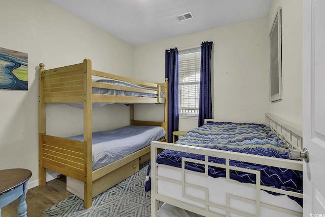 bedroom with visible vents, baseboards, and wood finished floors