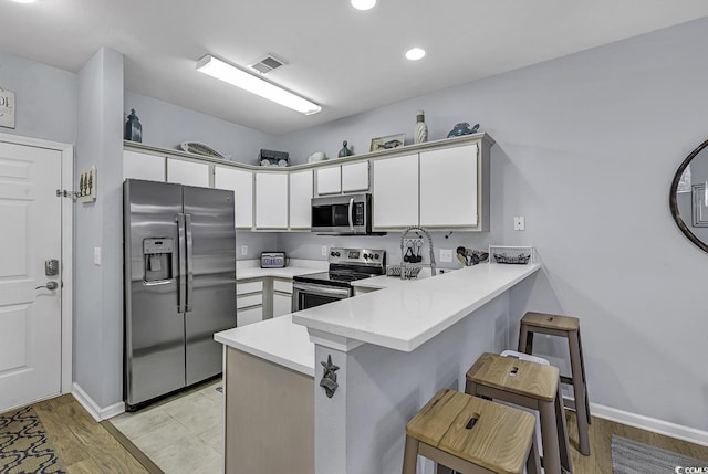 kitchen with visible vents, a peninsula, stainless steel appliances, and light countertops