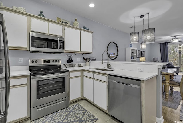 kitchen with open floor plan, light countertops, a peninsula, stainless steel appliances, and a sink