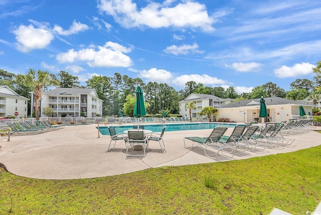 community pool with a patio area, fence, and a lawn