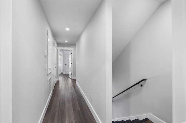 hall with an upstairs landing, recessed lighting, dark wood-type flooring, and baseboards